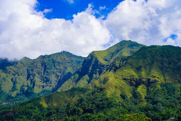 Panoramic view of green landscape with mountains, blue sky and white clouds from Selong Hill, Sembalun, Lombok, West Nusa Tenggara, Indonesia.