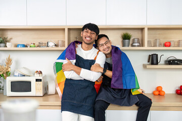 LGBT couple embracing with pride flag in the kitchen. Celebrating love and diversity.