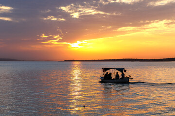 Fototapeta premium sunset on the lake and silhouette of a group of people in a boat watching sunset