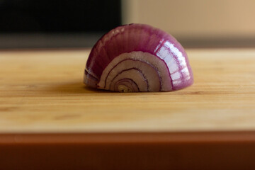 Close-up photo of a half purple onion resting on a wooden board.