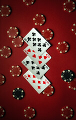 A set of four eights of playing cards laid out on a dark red surface, surrounded by colorful poker chips, creates a lively atmosphere for a game night