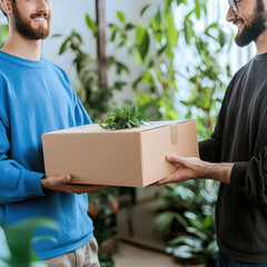Two men exchanging cardboard box with small plant on top, surrounded by indoor greenery, smiling warmly
