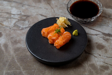 Delicate salmon nigiri elegantly arranged on a sleek black plate, accompanied by fresh wasabi and pickled ginger, perfect for sushi enthusiasts at a fine dining restaurant