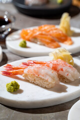 Delicate shrimp sushi elegantly arranged on smooth white plates, accompanied by wasabi and ginger, showcasing the artistry of culinary craftsmanship in an upscale dining setting