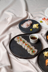 A beautiful arrangement of sushi on dark plates showcases fresh fish slices garnished with colorful...