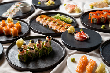 An array of beautifully crafted sushi delights awaits, featuring fresh ingredients like salmon, shrimp, and avocado ingeniously arranged on elegant black plates