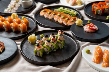 A lavish assortment of sushi highlights creative rolls, delicate sashimi, and vibrant garnishes on stylish black plates, inviting a culinary journey that tantalizes the senses