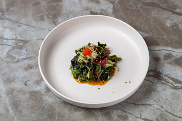 A vibrant dish showcases an array of greens, artfully arranged with a touch of bright toppings, exuding freshness and creativity. This modern culinary art delights the senses