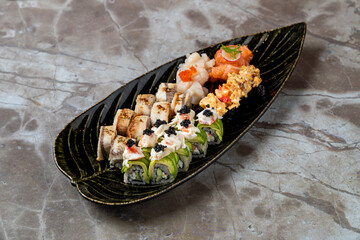 A beautifully arranged sushi platter features a variety of rolls atop a decorative leaf-shaped dish, highlighting fresh ingredients and culinary artistry at a vibrant dining spot