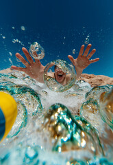 Young boy reaching out through water bubbles – energetic underwater summer moment for aqua park and kids holiday content