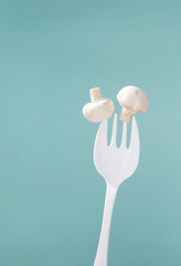 champignon on big white fork on green background