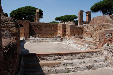OSTIA ANTICA, ITALY, JULY 24, 2022: Ancient Roman ruins with brick walls, stone floors, and trees...