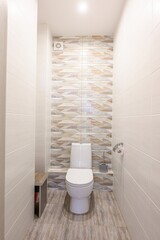 clean, narrow bathroom features white walls and a geometric-tiled accent wall behind a white toilet