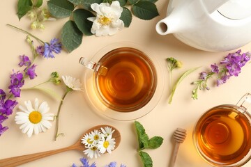 Aromatic herbal tea in glass cups, different flowers, mint and teapot on beige background, flat lay
