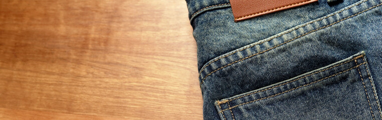 Jeans pants on the table wood background. back pocket of blue jeans, denim texture.
