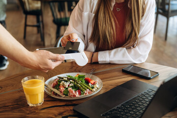 Wireless payment by using smartphone. Woman n the cafe restaurant