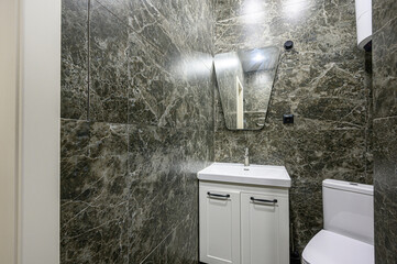 modern bathroom features marble-patterned walls, a white vanity with a sink, and a stylish mirror....