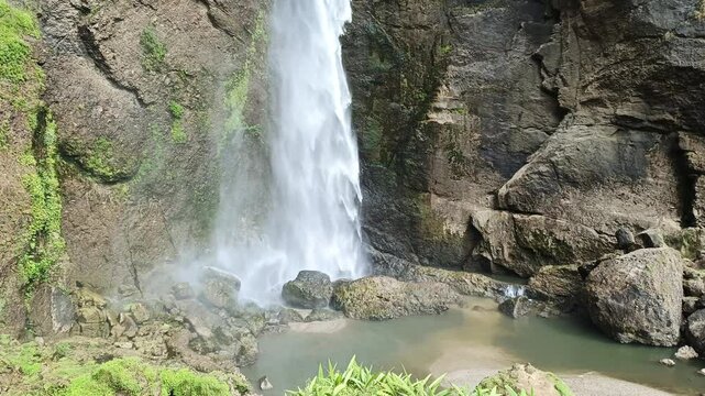 footage of a waterfall in the middle of the forest with a very beautiful cliff, the name is Sarasah Barasok waterfall in West Sumatra