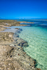 A Japanese man squats and takes photos of the clear waters of Cape Bisezaki, on Okinawa's main...