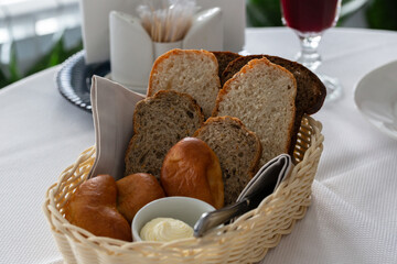 Bread in basket. White and black sliced bread, butter and pies in a basket on the table in the restaurant