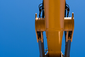 Looking up at an exavator arm against the blue sky