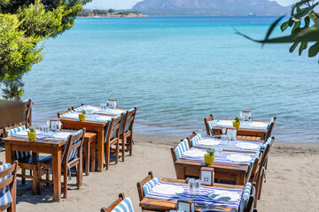 Waterfront dining area with white tables and clear blue water