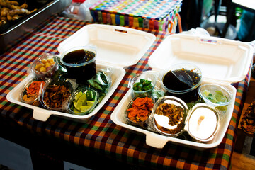 Traditional local thai snack food dessert Miang Kham or royal savoury leaf wrap with side dish appetizer with caramel sweet sauce for people buy eat drinks at street market bazaar in Bangkok, Thailand