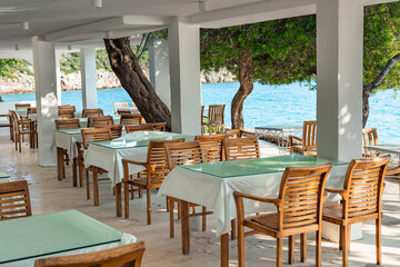 Cozy seaside terrace with wooden furniture and stunning ocean view during sunny daytime