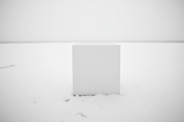 Obraz premium Minimalist white cube in snowy landscape under grey sky. AI-generated.