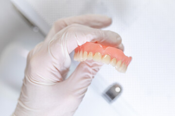 Removable dental prosthesis with visible wear and gloved hand © SWMedia