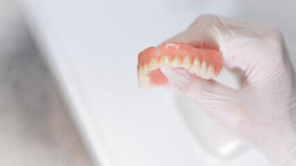 Close-up of worn dental prosthesis held by gloved fingers