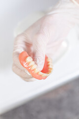 Used upper dental prosthesis held with gloved hand © SWMedia