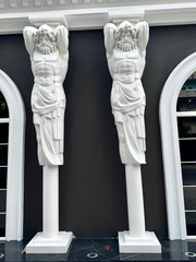 view of two white stone male statues on the facade of a building in Tirana, Albania
