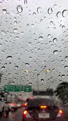 Raindrops on car windshield looking out at traffic