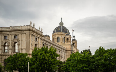 Historic European building with dome and statues under cloudy sky in springtime