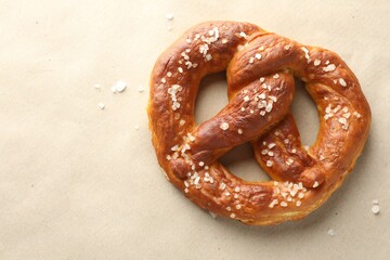 Tasty pretzels with salt on beige background, top view. Space for text
