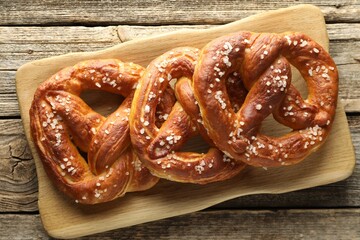 Tasty pretzels with salt on wooden table, top view