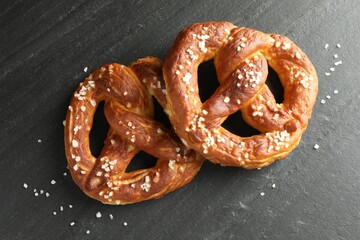 Tasty pretzels with salt on black table, flat lay