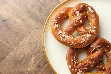 Tasty pretzels with salt on wooden table, top view. Space for text