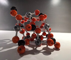 Molecular model with orange and black spheres representing atoms