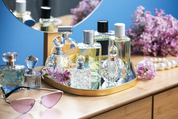 Bottles of perfumes, accessories and lilac flowers on wooden table