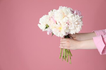 Woman with bouquet of beautiful peonies on pink background, closeup. Space for text