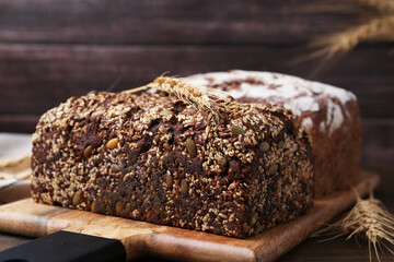Freshly baked loaves of bread and spikes on wooden table, closeup
