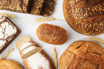 Freshly baked loaves of bread and spikes on light textured table, flat lay
