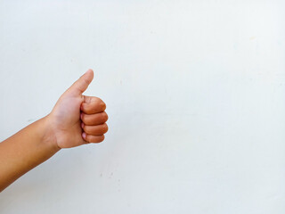 A kid's hand giving a thumbs up gesture on white background. Asian kid's hand gesturing thumbs up