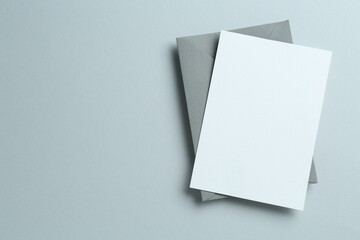 Blank invitation card and envelope on grey background, top view. Space for design