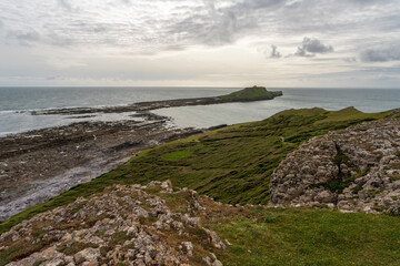 Worm Head Point pictured at low tide revealing the causeway of rocks on which people can cross to the furthest islands,