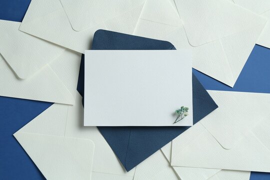 Blank invitation card and envelopes on blue background, flat lay. Space for design