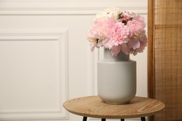 Beautiful peonies in vase on wooden table indoors. Space for text