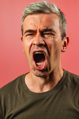 Man expressing strong emotions against a pink background